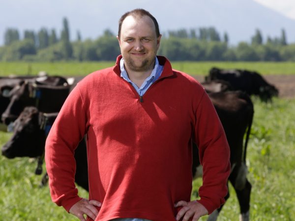 Rhys Roberts standing in paddock with cows